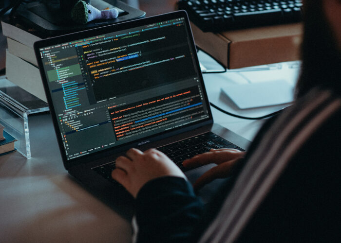 Macbook Pro laptop met code, gezien over de schouder van een persoon