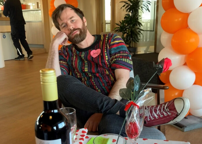 Foto van Joralf die naast een tafeltje zit, met daarop een fle wijn en rozen