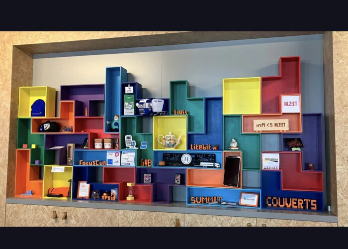 Foto van klantmuur bestaande uit opengewerkte tetrisblokken met daarin logos en swag van de klanten van Infi