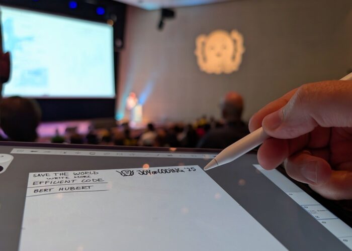 Close up van een tablet waarop getekend wordt met witte pen, conferentiezaal op de achtergrond met blurry Octopus-icoon op de muur geprojecteerd