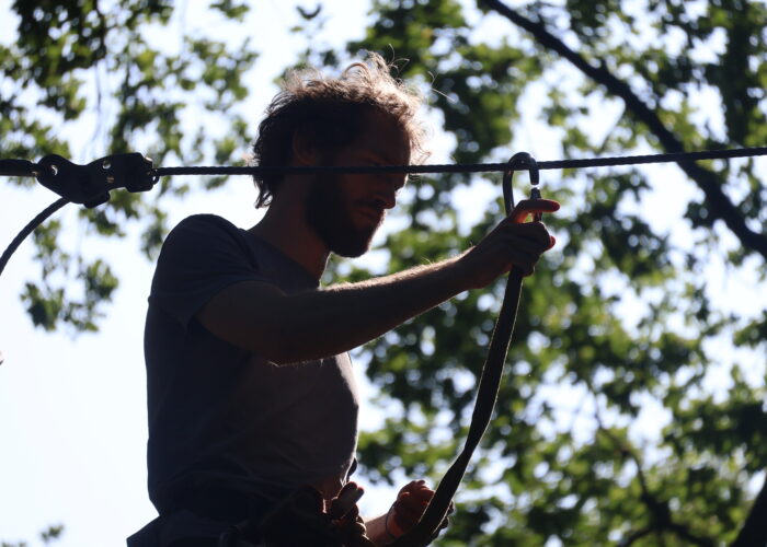 silhouet van bovenlichaam van persoon die een touw vast heeft. Bos op de achtergrond.