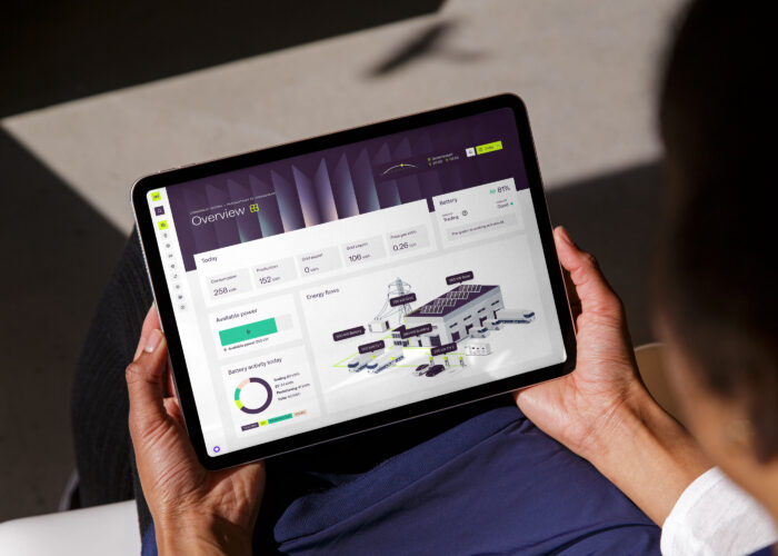 Tablet in handen van een persoon, op het tablet een visual van energiestromen voor een bedrijf.